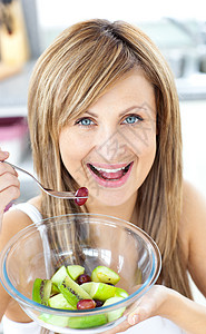 欢乐女人吃水果沙拉 在Ki的相机上微笑着笑金发饮食奇异果水果女性甜点厨房营养食物沙拉图片