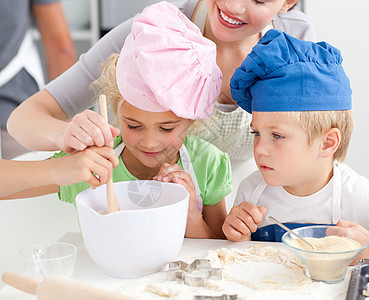 两个孩子和他们的母亲正在搅拌饼干的准备工作图片