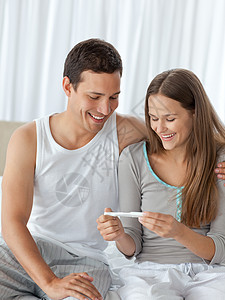幸福的一对夫妇在床上看怀孕测试已婚房子微笑男人几个月睡衣黑发孕吐女士卧室图片
