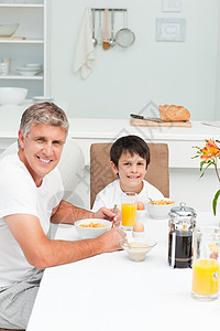 父亲和儿子一起吃早饭笔记本早餐杯子闲暇电脑家庭男性桌子食物果汁图片