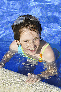 女孩在夏天游泳池中微笑和快乐闲暇蓝色游泳童年孩子娱乐乐趣眼睛幸福水池图片