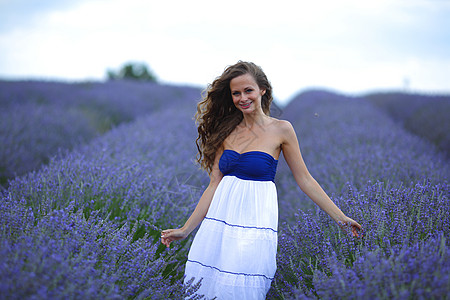 女性站在紫衣草地上快乐晴天天空自由休闲黑发旅行喜悦农村女孩图片