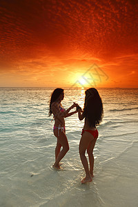 两个女人在海滩上享受日落假期阳光闲暇场景活力海洋自由旅行喜悦海浪图片