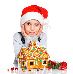 穿着圣诞老人帽子的小男孩和姜饼屋糖果传统微笑幸福饼干庆典沙漠房子蛋糕乐趣图片