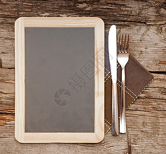 用刀和叉子躺在旧木板桌上的菜单黑板服务用具橡木检查桌布粉笔公告广告牌框架用餐图片
