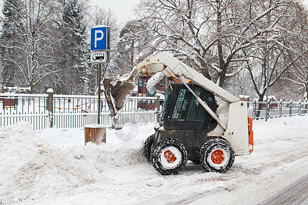 小型挖土机山猫在街上工作推土机挖掘机风暴雪堆天气城市街道环境季节搬运工图片