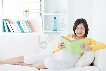 亚裔孕妇喜悦长椅阅读女士享受母亲房间沙发教育幸福图片