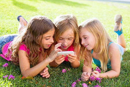 儿童朋友朋友女孩与智能手机在网上玩电话享受公园草地乐趣教育团体学生游戏幸福图片