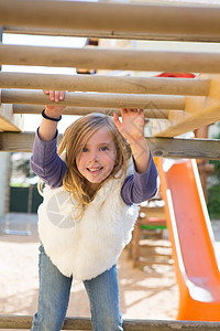 女孩在游乐场玩耍时用木棍挂吊微笑女儿背心眼睛金发女郎闲暇孩子们乐趣快乐操场图片