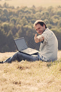 年轻人用笔记本电脑坐在山坡的草地上商业城市男性场景风景地平线商务全景人士自由图片