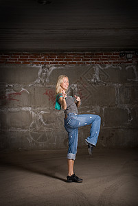 在灰砖墙上跳舞的美丽舞女衣服慢跑裤姿势女士运动鞋培训师演员运动女性衬衫图片