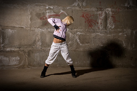 在灰砖墙上跳舞的美丽舞女运动鞋女性女士成人姿势街道培训师裤子运动演员图片