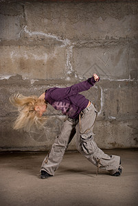 在灰砖墙上跳舞的美丽舞女霹雳舞运动鞋慢跑裤衣服长发女士夜生活青少年演员衬衫图片