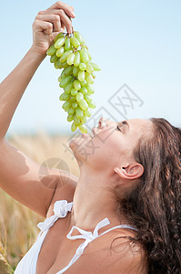 完美的女人在小麦田里吃葡萄食物野餐国家自由农场假期农业女孩闲暇水果图片
