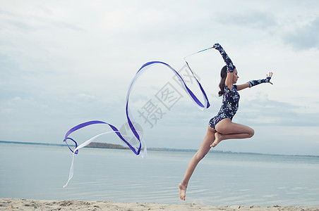年轻体操女子与丝带跳舞微笑海滩乐队生活天空演员运动员海洋女士运动图片
