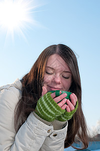 女孩在冬季野餐时喝着热茶太阳围巾蓝色天空女士女性光束咖啡长发黑发图片