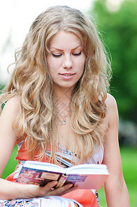 美丽的年轻女性阅读书裙子故事眼睛学生女士水果头发草地闲暇教科书图片