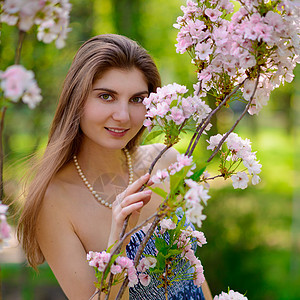 有着粉红樱花花的年轻美女裙子女性微笑头发魅力皮肤眼睛女孩公园樱花图片