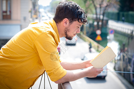 青年男子阅读书城市教育黄色衬衫年轻人学生阅读阳台学习文化图片