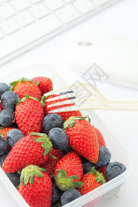 健康午餐 办公室配有草莓和蓝莓混合桌子老鼠商业电脑塑料休息水果食物键盘时间图片