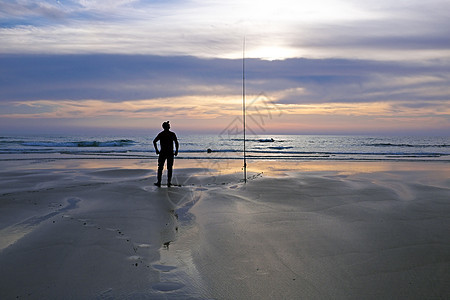 黄昏时沙滩上孤单的渔夫图片