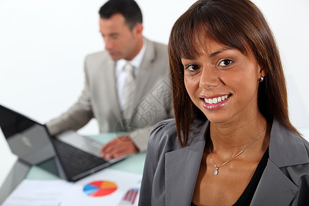 站在同事和笔记本电脑面前的笑脸女商务人士图片