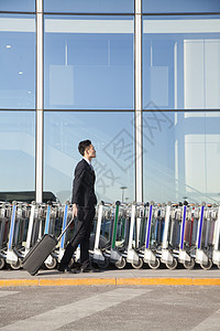 机场一排行李车厢旁边携带手提箱的旅客组织窗户旅游停车场路面牵引机动性衣冠航班奢华图片
