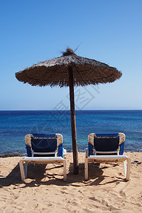 热带海滩的雨伞下的太阳椅子木头地平线海岸线海岸遮阳棚阳光孤独座位支撑晴天图片