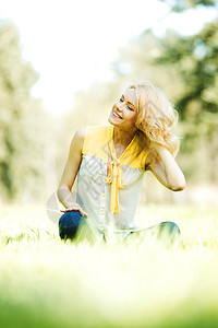 坐在草地上的女人喜悦微笑黄色快乐晴天女孩女性公园闲暇自由图片