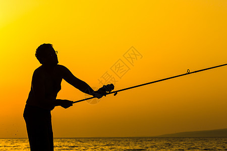 富彩的日落时 渔夫在海滩上的轮廓男人运动海鲜垂钓者假期海洋卷轴天空食物海岸图片