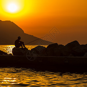 富彩的日落时 渔夫在海滩上的轮廓垂钓者男人卷轴海洋海岸食物橙子娱乐闲暇假期图片