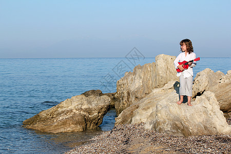带着吉他的女孩站在岩石上图片