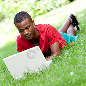 带着笔记本坐在草地上的年轻 微笑着笑容的非洲学生幸福黑色男性快乐教育男人电脑多样性男生成功图片