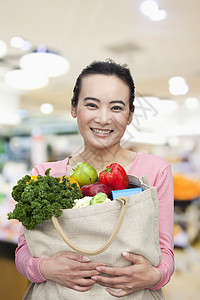 持有水果和蔬菜购物袋的中年成年妇女(含水果和蔬菜)图片
