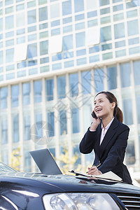 拥有使用电话和笔记本电脑汽车的女商务人士图片