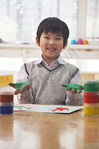 北京艺术课中微笑的男学生手指绘画肖像校服俏皮小学活动创造力桌子学习童年头发课堂图片