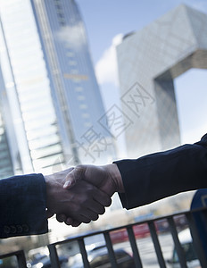两名商务人士在北京闭路电视大楼握手的近距离亲近图片
