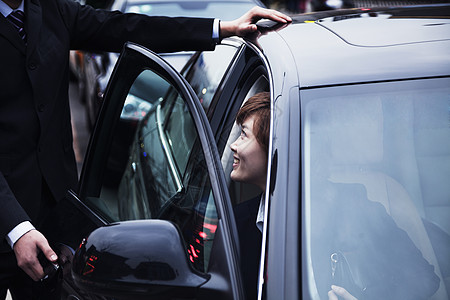 在北京的白天 商务人士为女商务人士打开汽车门图片