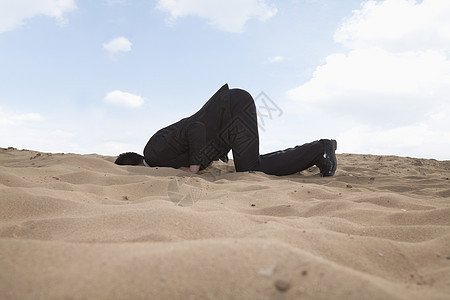 年轻的商务人士 带着头跪在沙子里的洞里公司商业沙漠天空套装阶层阳光搜索气候挑战图片