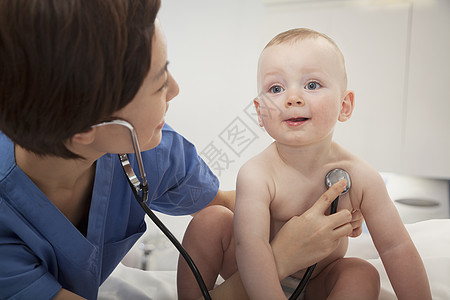 微笑的医生在医生办公室用听诊器检查婴儿的心跳棕色职业童年保健医护人员摄影医学福利诊所男婴图片