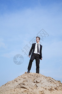 青年独居商务人士站在沙漠的山丘上图片