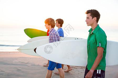 在海滩岸边行走的少年男孩天空太阳男孩们微笑波浪运动团体男人派对冲浪者图片