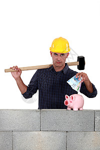 建筑工人把钱放进小猪银行里图片