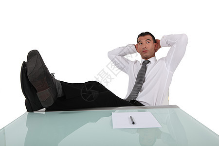 青年商务人士在桌子上和头后面用双腿断腿休息图片