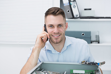 在开张的电脑前 被叫来时微笑着的计算机工程师的肖像硬件固定电话技术科技男人沟通电子产品修复修理工技术员图片