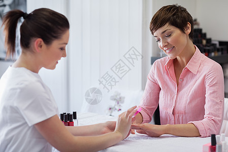 女人在美甲沙龙修指甲顾客手指幸福搪瓷美容桌子治疗指甲油女性职业图片