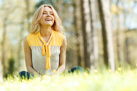 坐在草地上的女人晴天自由微笑喜悦快乐公园闲暇绿色黄色女孩图片