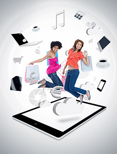 两个微笑的女人在 tablet p 上跳跃朋友购物牛仔裤笔记本经济平板电脑触摸屏计算机音乐图片