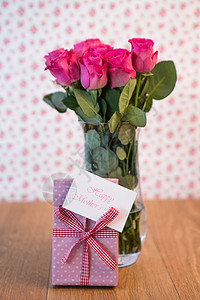 花瓶里的粉红玫瑰和粉红色的礼物 紧靠着它 母亲日卡图片
