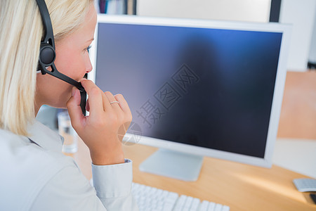 戴耳机 看电脑屏幕的女商务人士图片